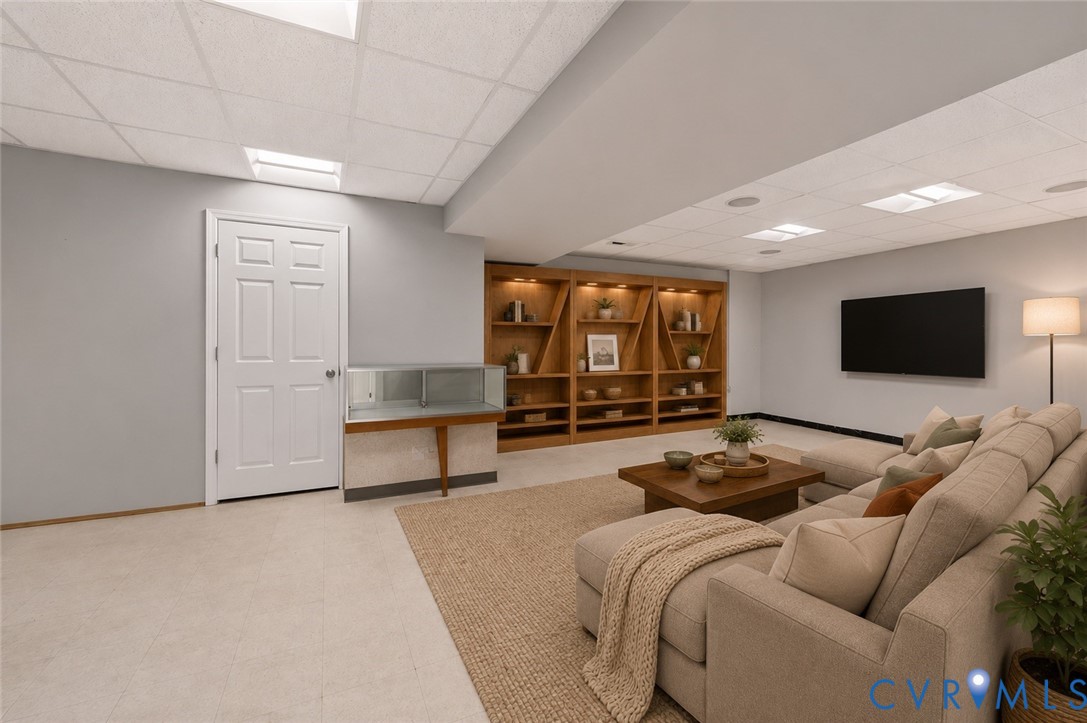 Finished interior space featuring a drop ceiling with recessed lighting, custom built-in wooden shelving with integrated accent lighting, and a six-panel interior door