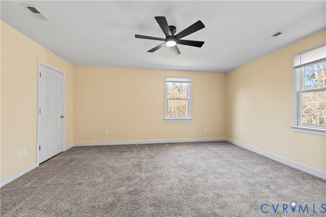Neutral-toned walls, grey carpeting, multi-pane windows, and a matte black six-blade ceiling fan with integrated lighting