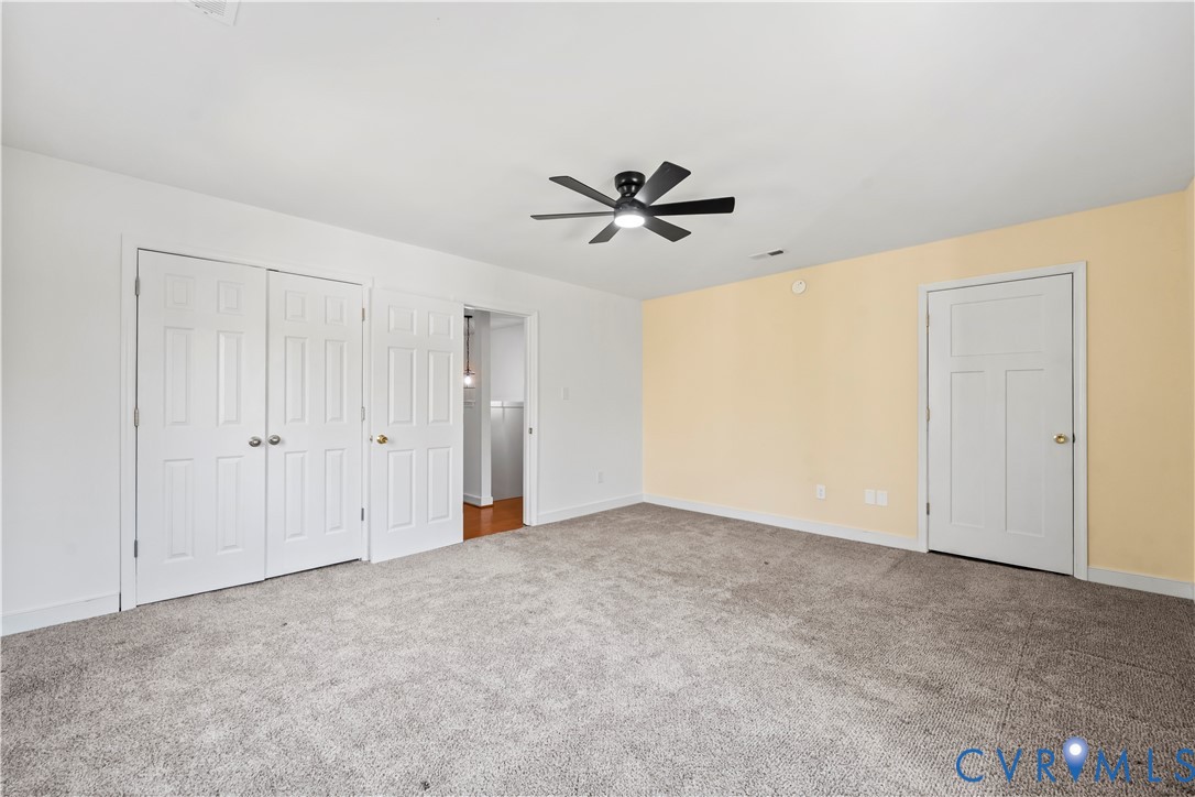 Neutral-toned wall paint, wall-to-wall carpeting, white six-panel interior doors, and a black ceiling fan with integrated light fixture