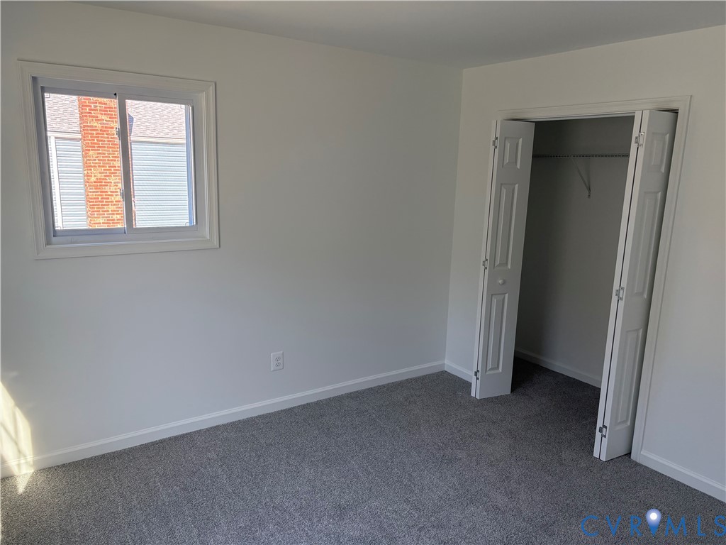 Bedroom 3 featuring neutral-toned carpeting, single-pane sliding window, and a built-in closet with six-panel bifold doors