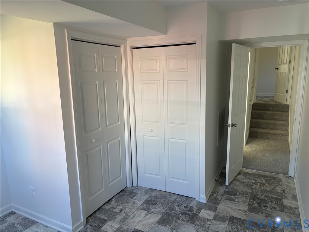 Neutral-toned multi-format flooring, two sets of white six-panel bi-fold closet doors, and interior paneled doors