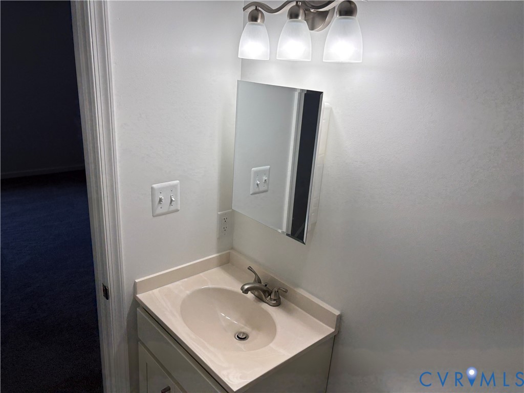 Vanity with integrated basin, solid-surface countertop, three-light brushed nickel fixture, and rectangular medicine cabinet