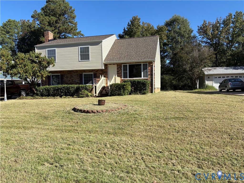 Split-level exterior featuring a brick and siding facade, chimney, shingled roof, and a detached garage