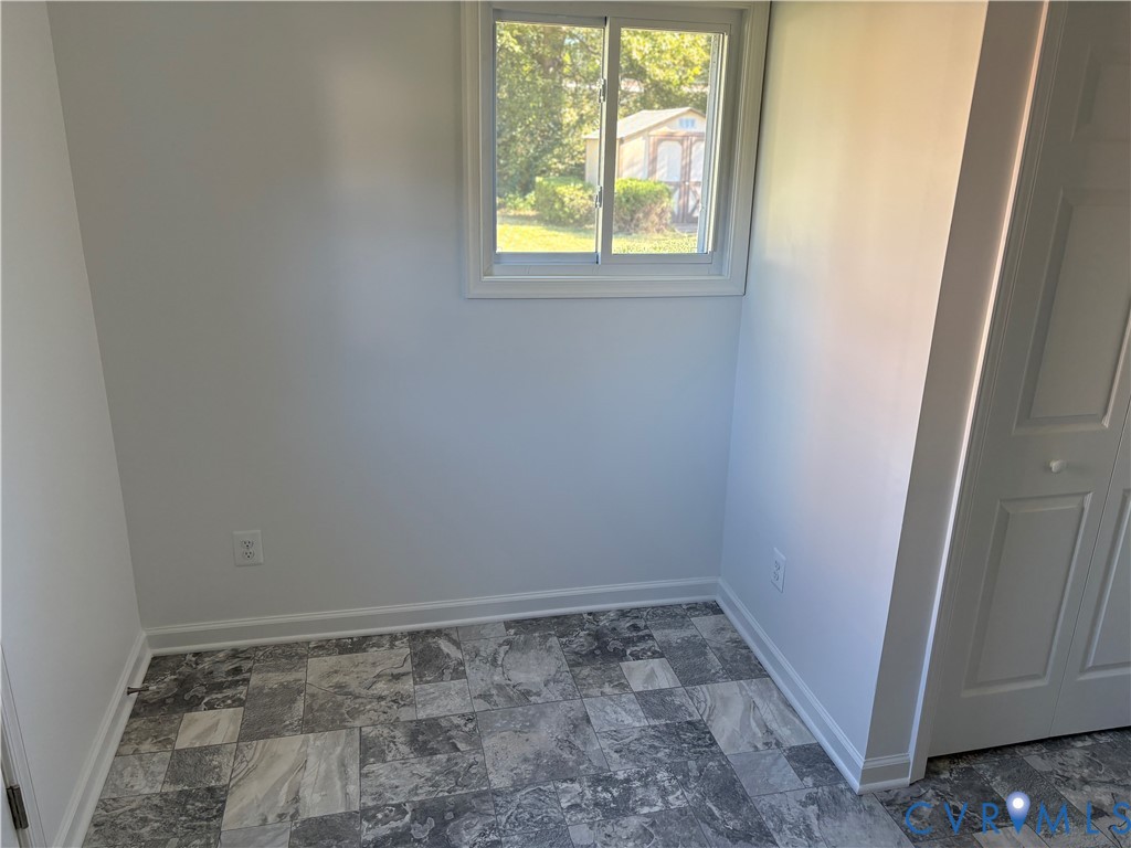 Utility Room featuring stone-patterned tile flooring, a sliding window with white trim, and a multi-panel closet door