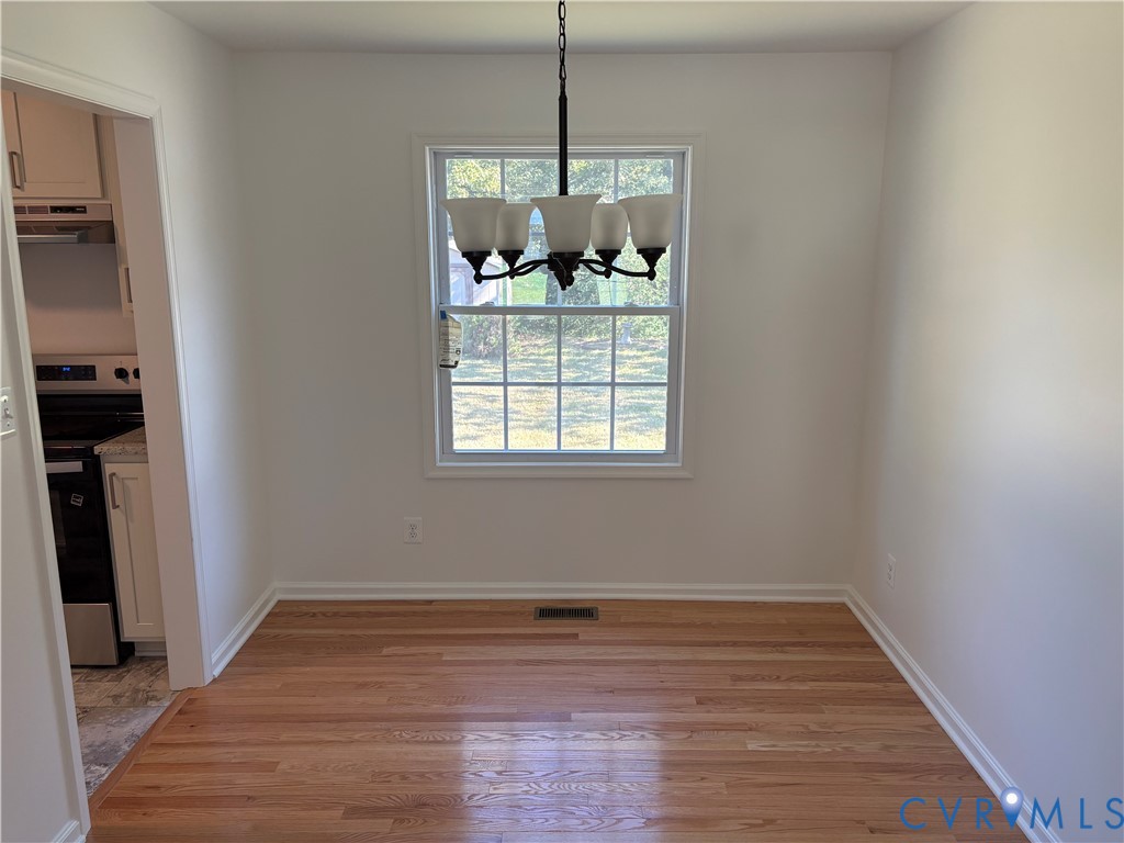 Dining room Wood-finish flooring, and five-light chandelier with frosted glass shades