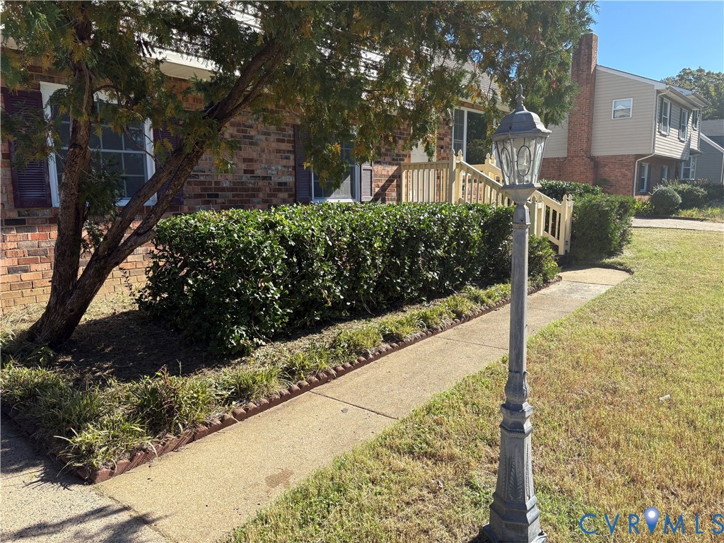 Brick exterior featuring a concrete walkway, decorative metal post light, and built-in railing