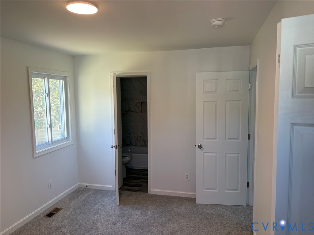 Primary Bedroom Neutral interior space featuring neutral wall-to-wall carpeting, white six-panel interior doors, and a double-hung window