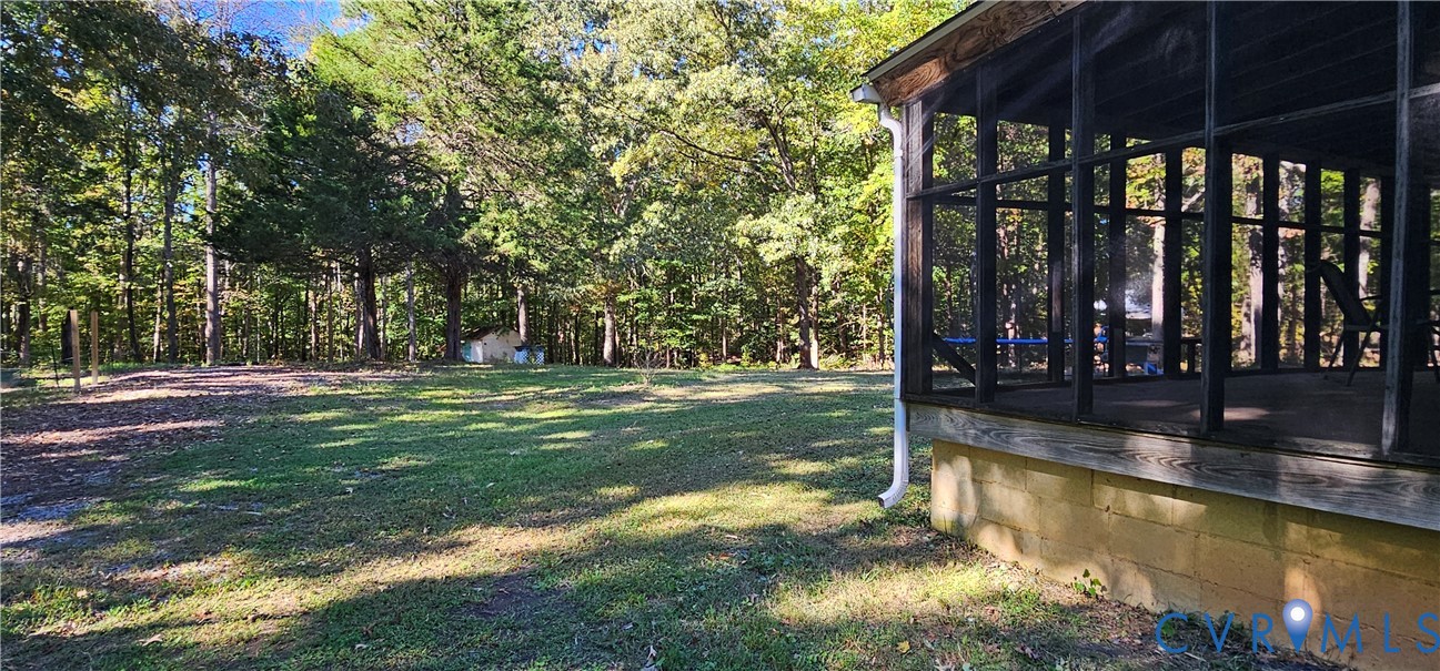 Screened porch with a dark frame, concrete block foundation, and exterior yard featuring mature trees and a grassy lawn