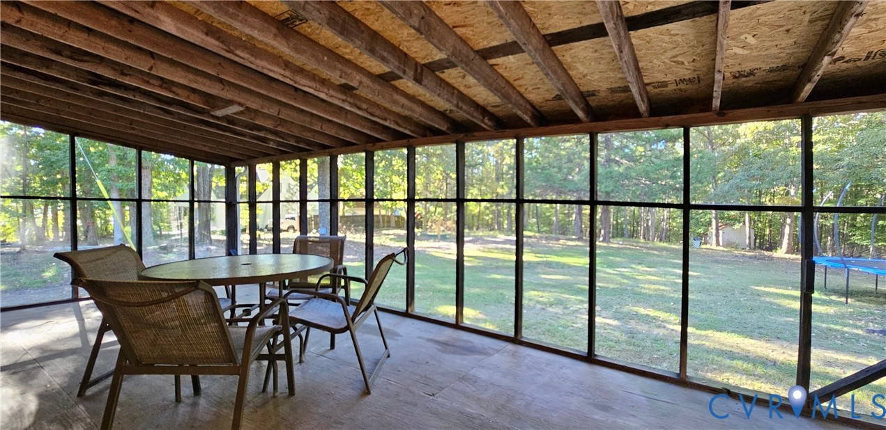 Enclosed porch featuring exposed wood-beam ceiling, full-length window screens, and solid surface flooring