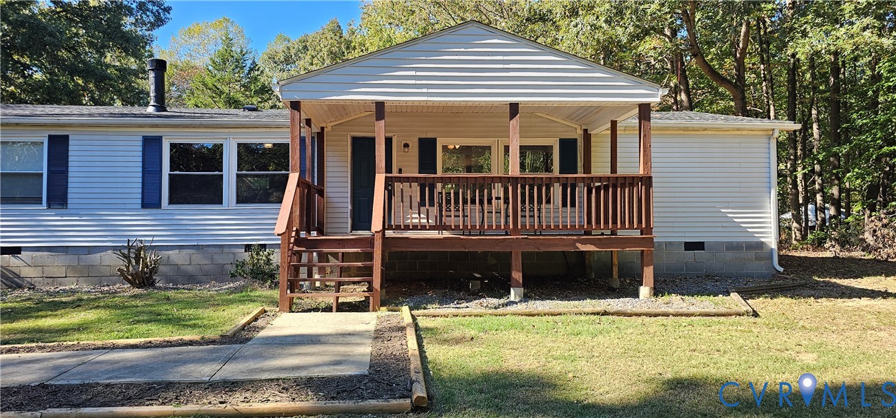 Exterior facade featuring horizontal siding, a covered front porch with wooden railings, and a concrete walkway