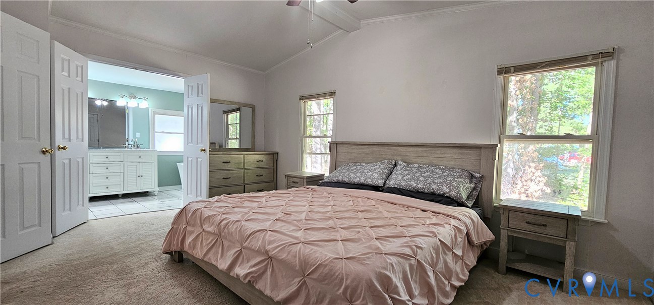 Vaulted ceiling with an attached light fixture and neutral wall-to-wall carpeting, featuring dual window placements and double-door entry to the bathroom