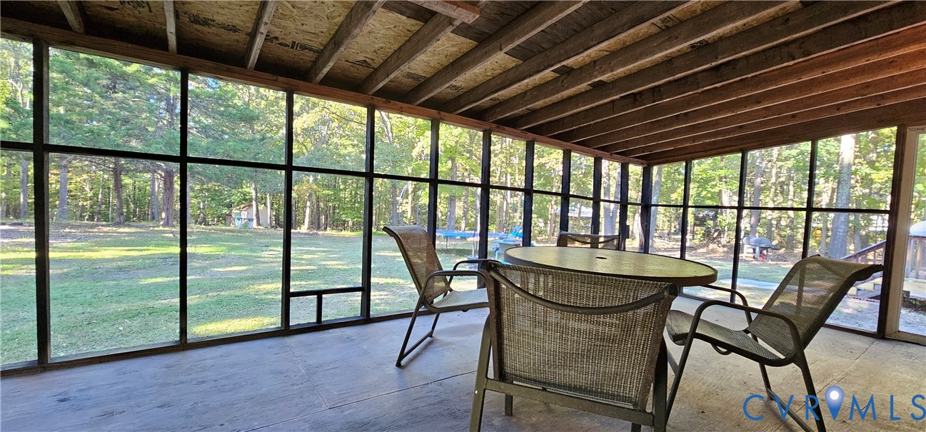 Screened-in porch featuring a flat-panel ceiling with exposed wooden rafters and full-wall mesh screening