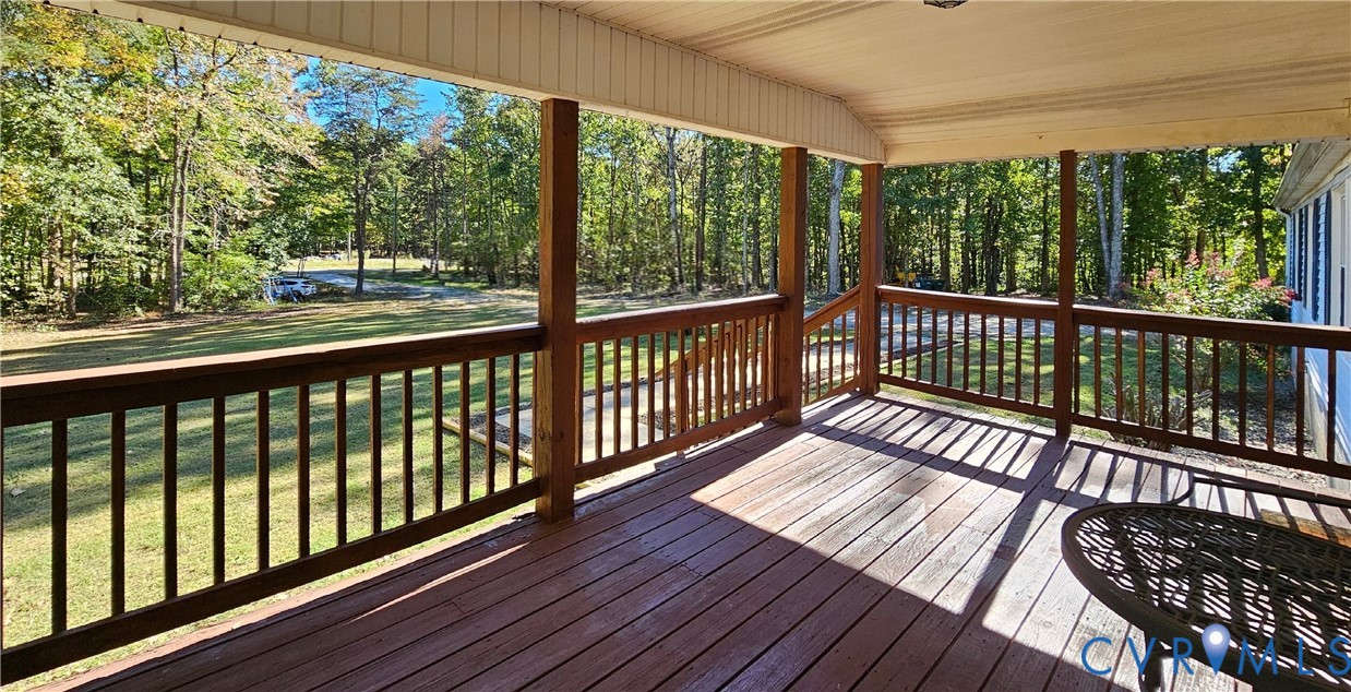 Covered rear deck featuring wood decking, wood railing, and a beadboard ceiling