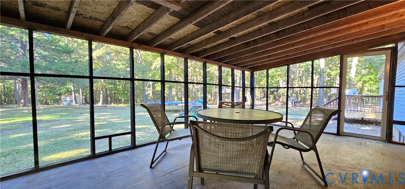 Screened-in porch featuring a wood-beam ceiling, full-height window screening, and a solid-surface floor