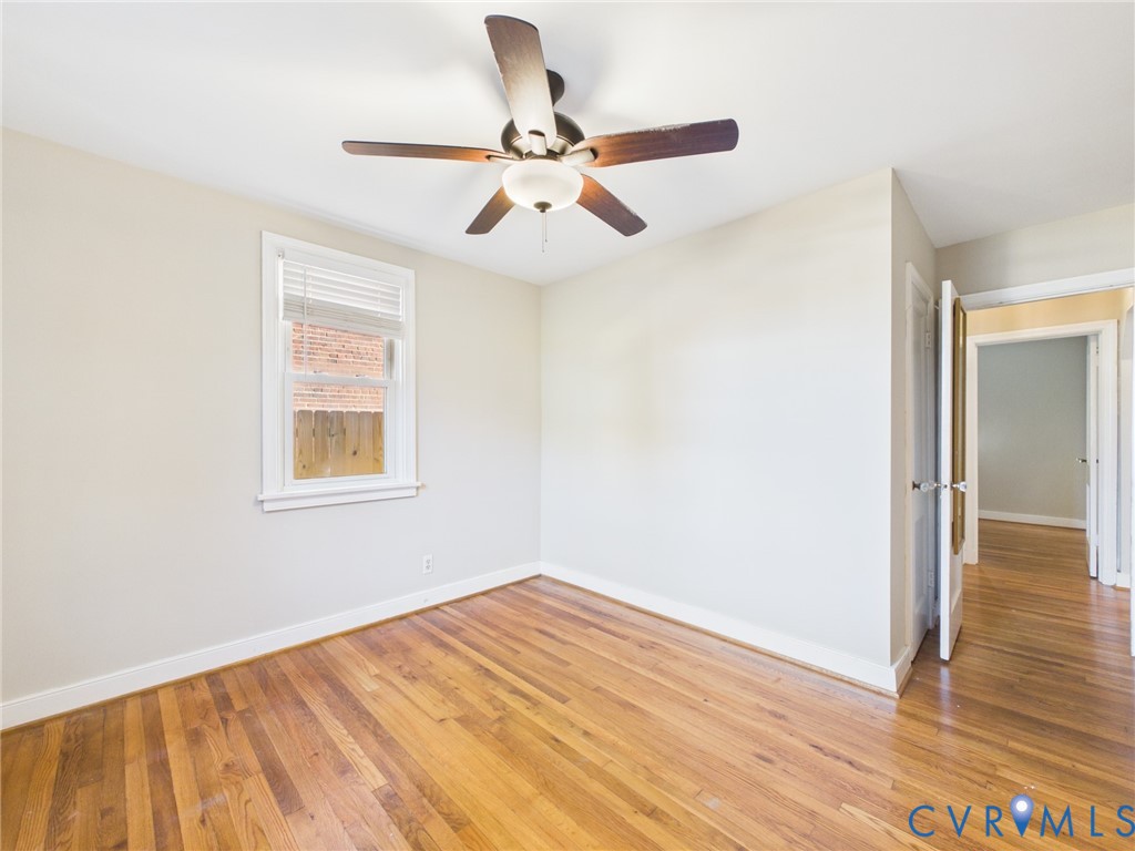 Interior room featuring wood-finish flooring, neutral wall paint, and a central ceiling fan with integrated lighting