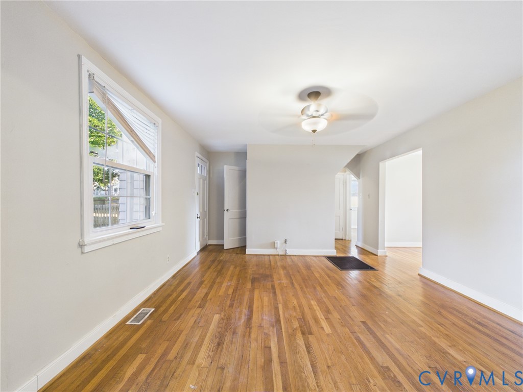 Hardwood flooring, multi-pane window, and ceiling-mounted light fixture with fan