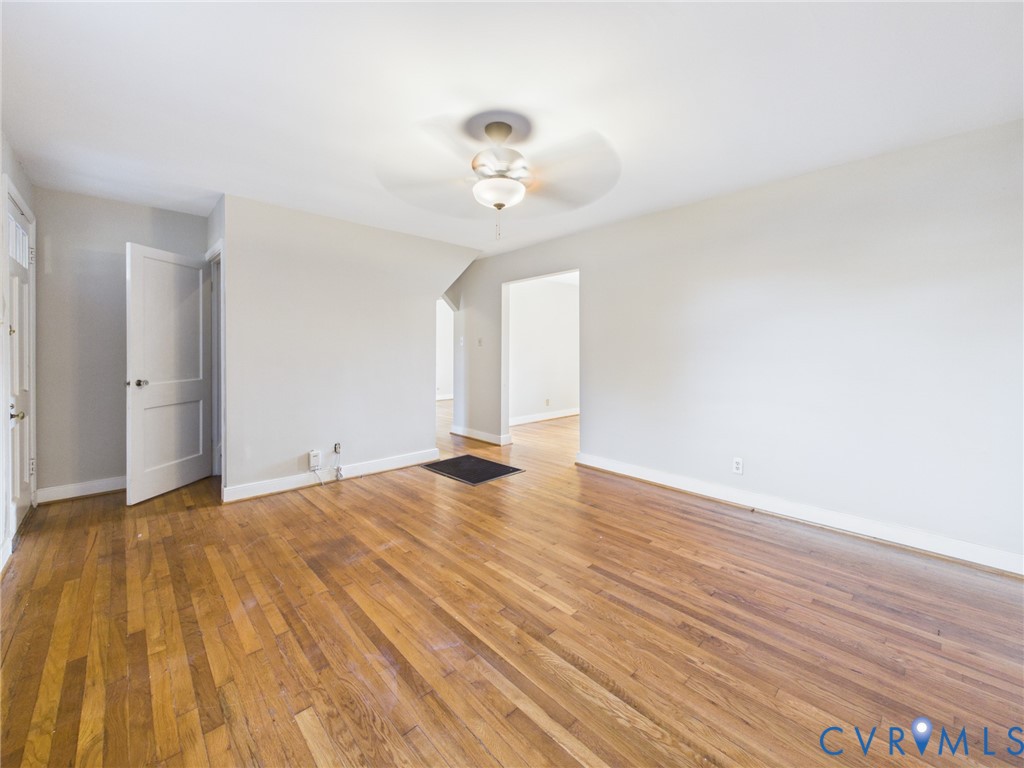 Interior space featuring wood-finish flooring, neutral wall paint, and a ceiling-mounted light fixture with an integrated fan