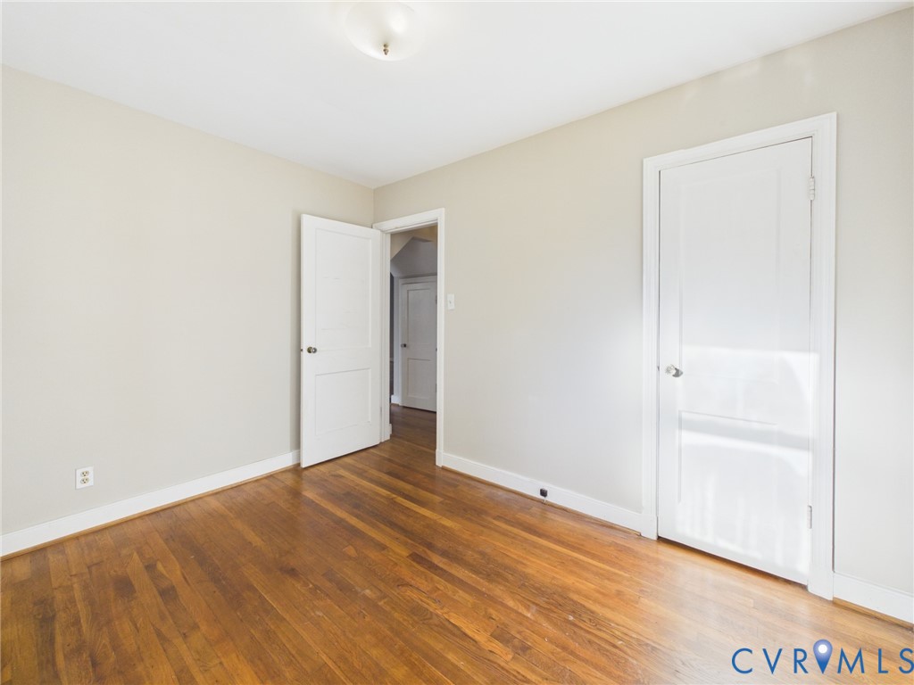 Room featuring wood-finish flooring, neutral wall paint, two-panel interior doors, and a ceiling-mounted light fixture