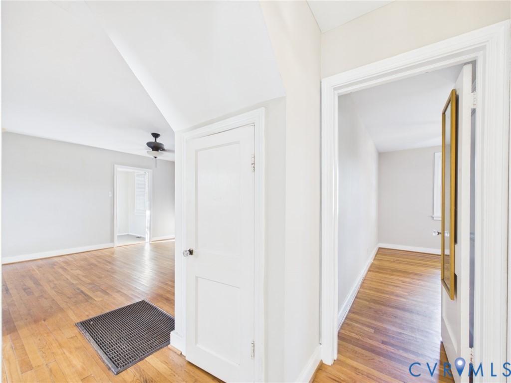 Interior featuring neutral-toned walls, wood-finish flooring, solid-core doors with traditional hardware, and a ceiling-mounted fan