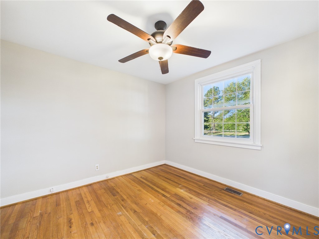 Hardwood flooring, multi-pane window with exterior scenery, and ceiling fan with integrated lighting
