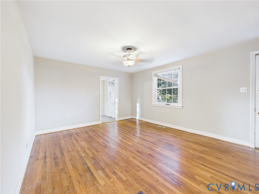 Interior room featuring wood-finish flooring, a multi-pane window, and a central ceiling fan with an integrated light fixture