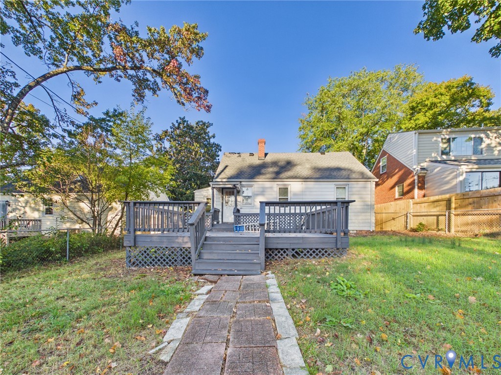 Raised rear deck featuring lattice skirting, stone-paver walkway, and mature trees