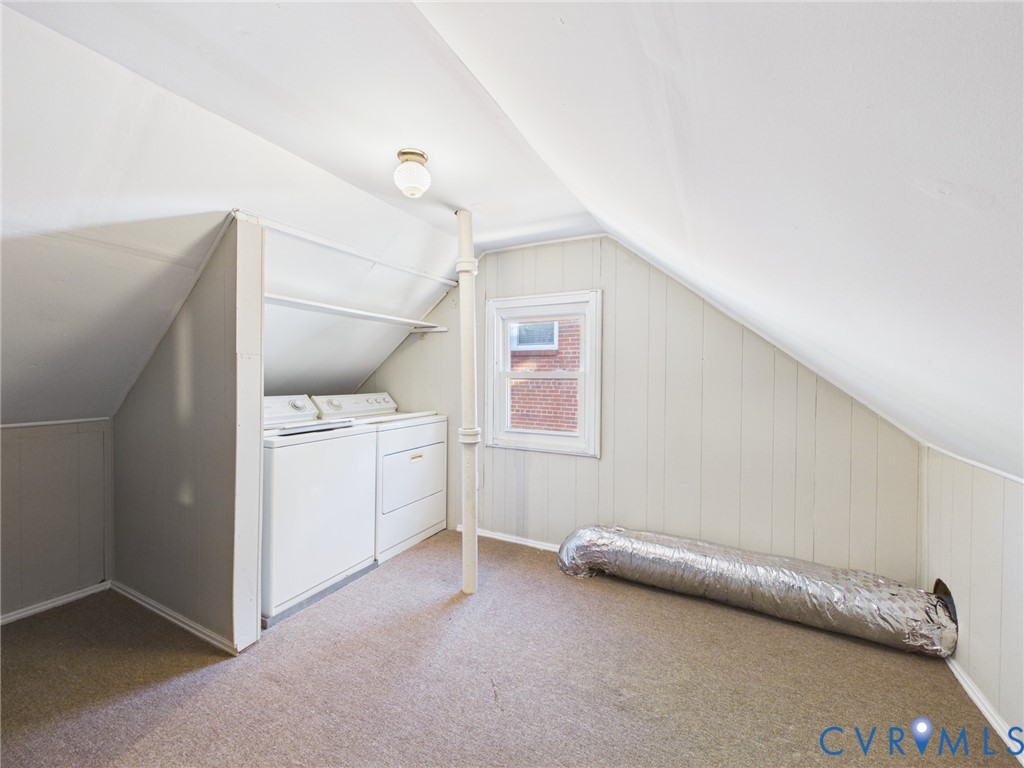 Dedicated laundry space featuring built-in cabinetry, vertical support column, single-hung window, and carpeted flooring