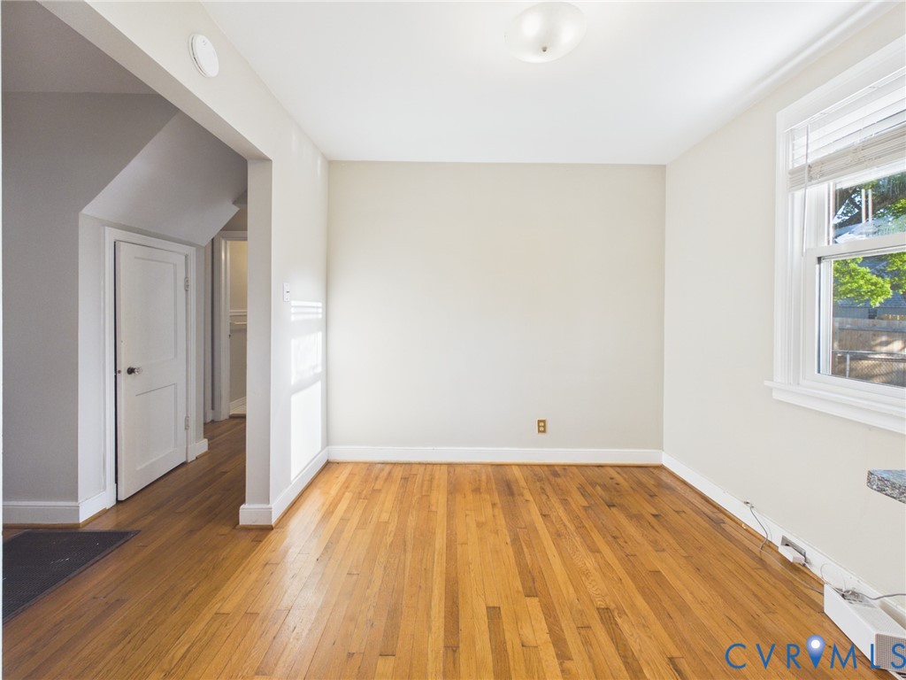 Interior space featuring wood-finish flooring, a double-hung window, and a multi-panel interior door