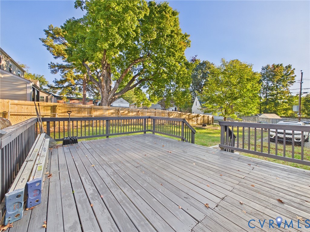 Elevated wood-plank deck with railing, natural backdrop, and fenced yard area