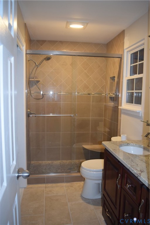 Ensuite Primary Bathroom featuring a walk-in shower with glass sliding doors, stone-finish tile surround, built-in corner shelving and bench, custom counter-height double sink vanity, and granite countertop.