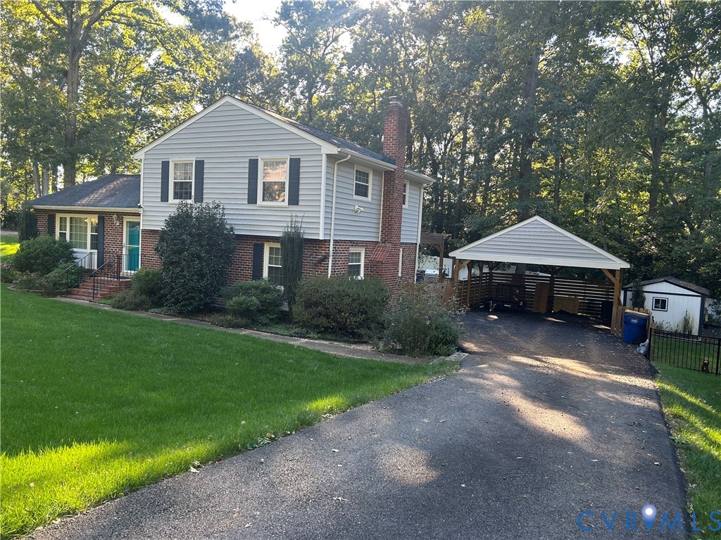 Split-level exterior featuring brick and siding facade, chimney, attached carport, and paved driveway Split-level exterior featuring brick and siding facade, chimney, attached carport, and paved driveway