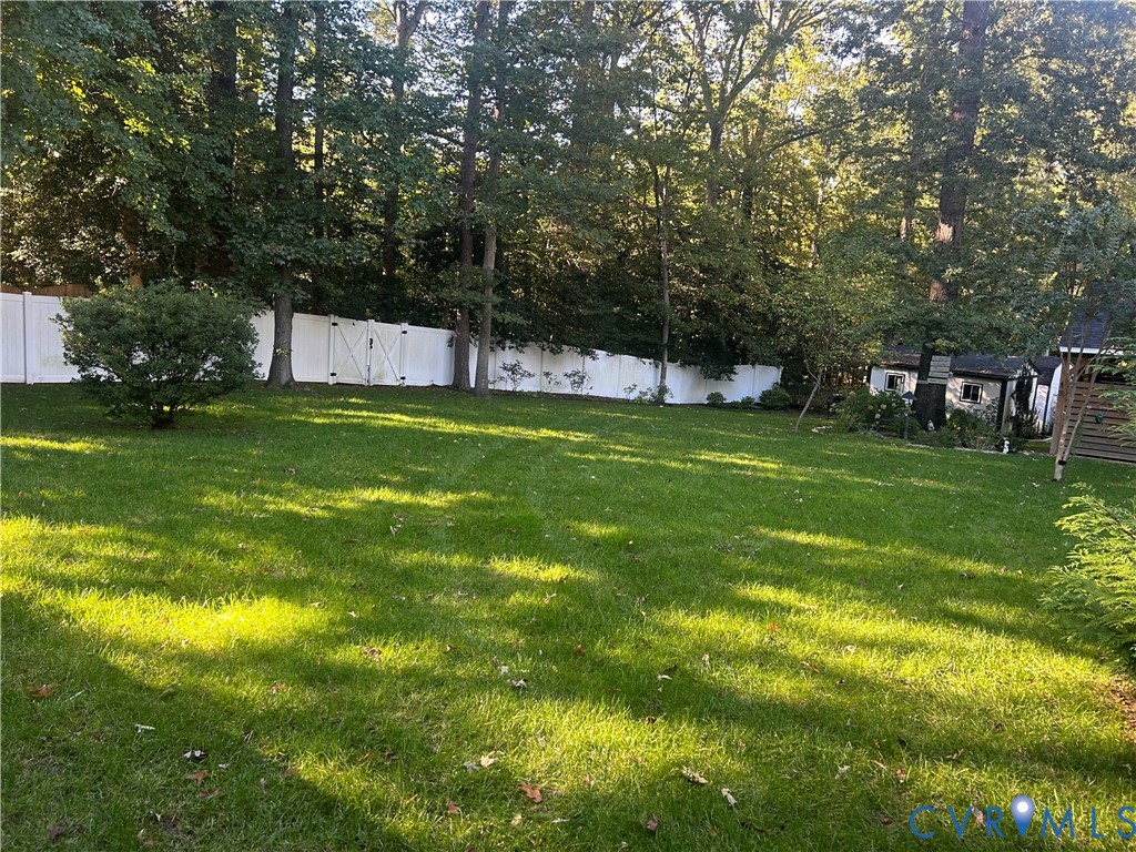 Expansive backyard featuring a level lawn, white vinyl fencing, and mature trees Expansive backyard featuring a level lawn, white vinyl fencing, and mature trees