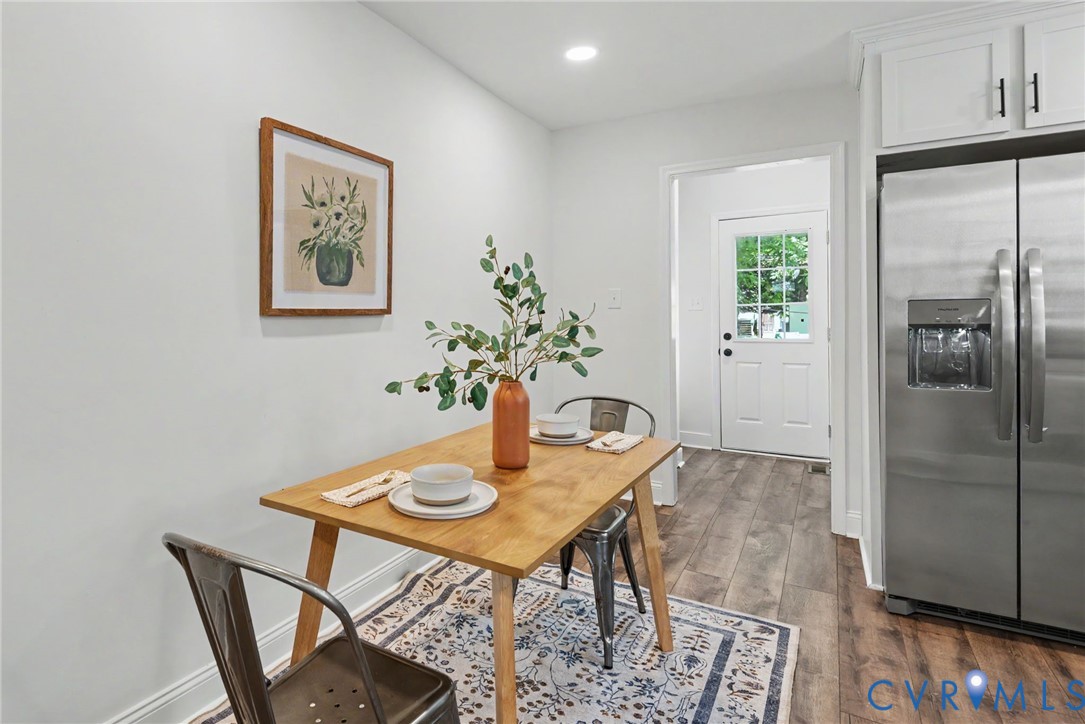 Wood-finish flooring, white shaker-style cabinetry, stainless steel side-by-side refrigerator with exterior water dispenser, and exterior-access door with inset window glass