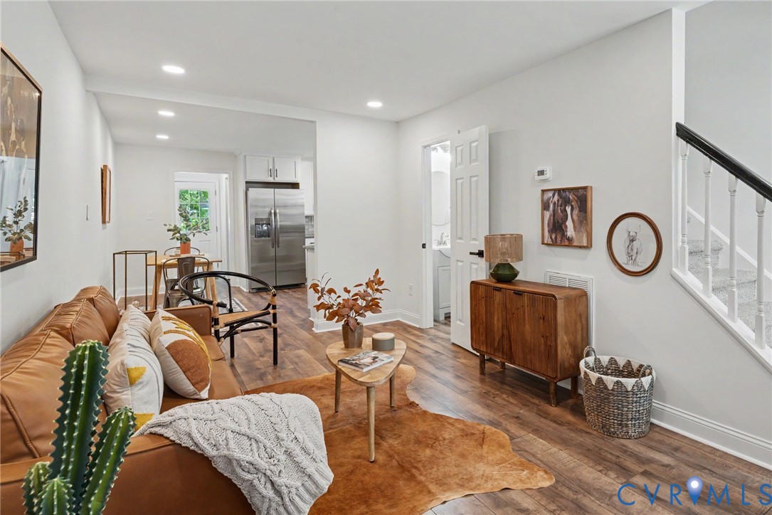 Interior space featuring wood-finish flooring, recessed lighting, and a staircase with white balusters and a dark handrail