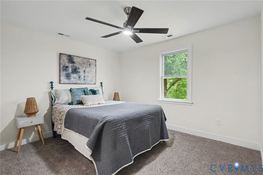 Neutral interior featuring wall-to-wall carpeting, a five-blade ceiling fan with integrated lighting, and a double-hung window