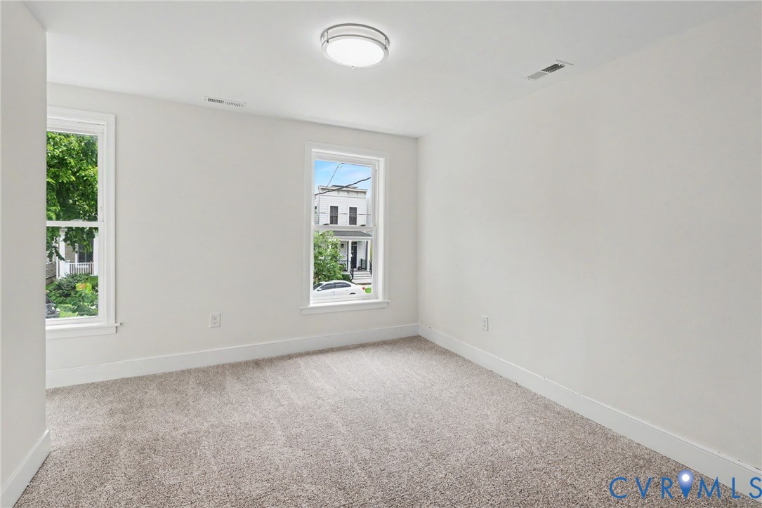 Neutral interior room featuring plush carpeting and dual windows with window casing
