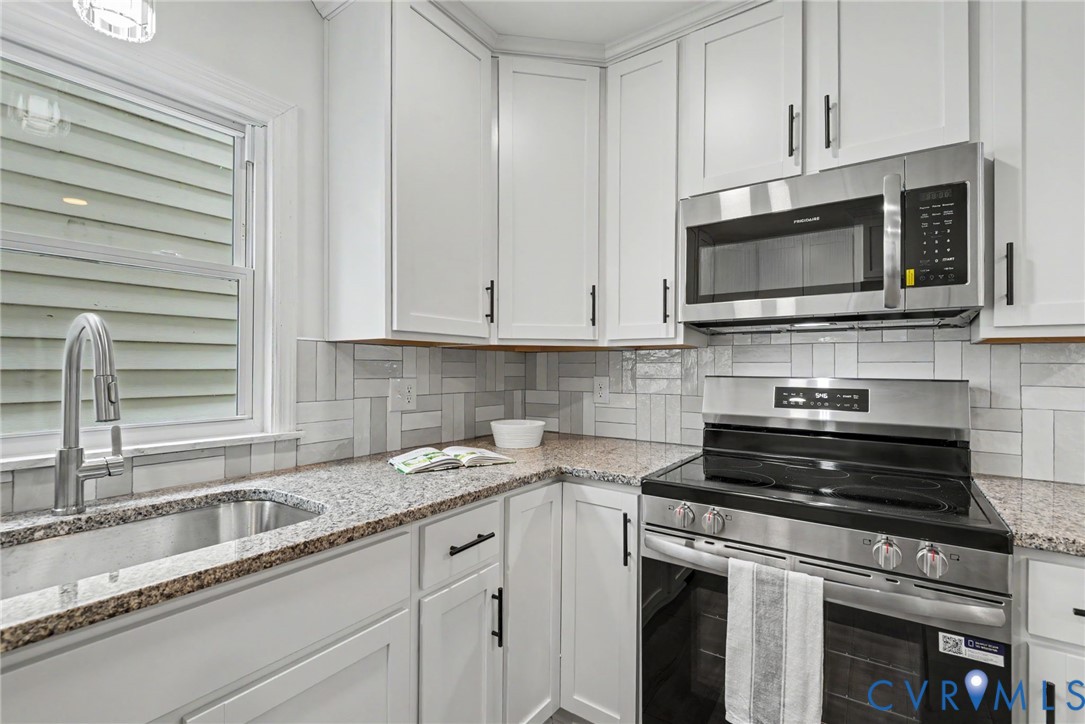 Kitchen featuring white shaker-style cabinetry, stone-finish countertops, stainless steel appliances, a herringbone-pattern tile backsplash, and a stainless steel gooseneck faucet
