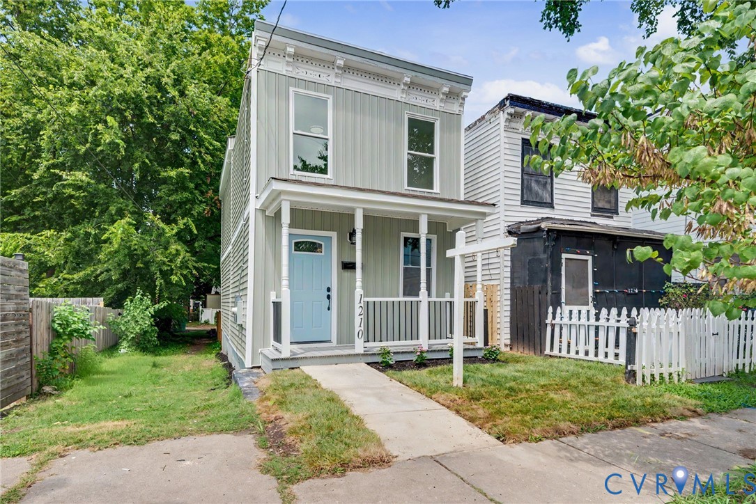 Vertical siding exterior with decorative corbel trim, covered front porch, and light blue entry door Vertical siding exterior with decorative corbel trim, covered front porch, and light blue entry door