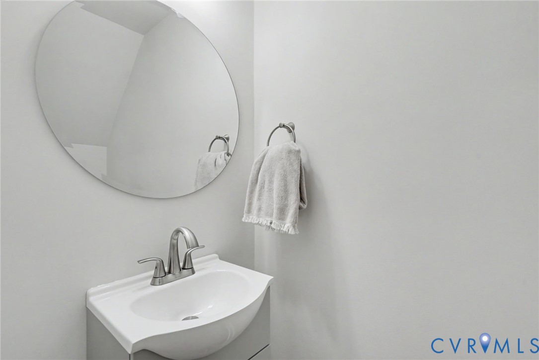 Wall-mounted oval mirror above a vanity with an integrated basin, brushed-metal centerset faucet, and circular towel ring