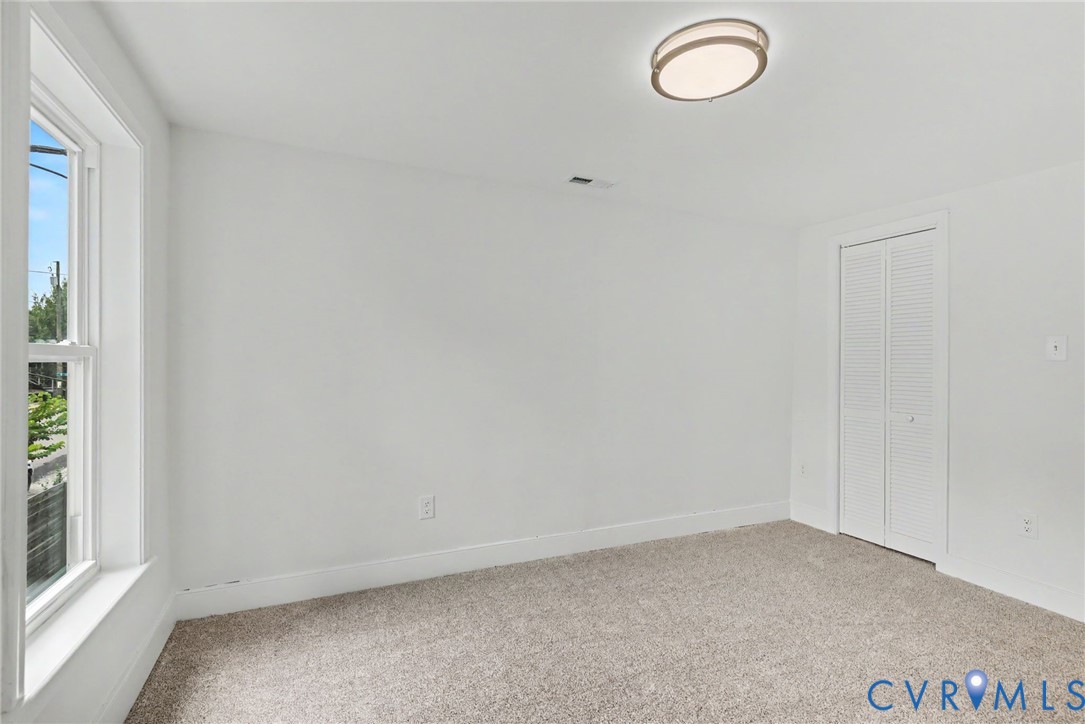 Room featuring neutral carpeting, a double-panel bifold closet, and a ceiling-mounted flush mount light fixture