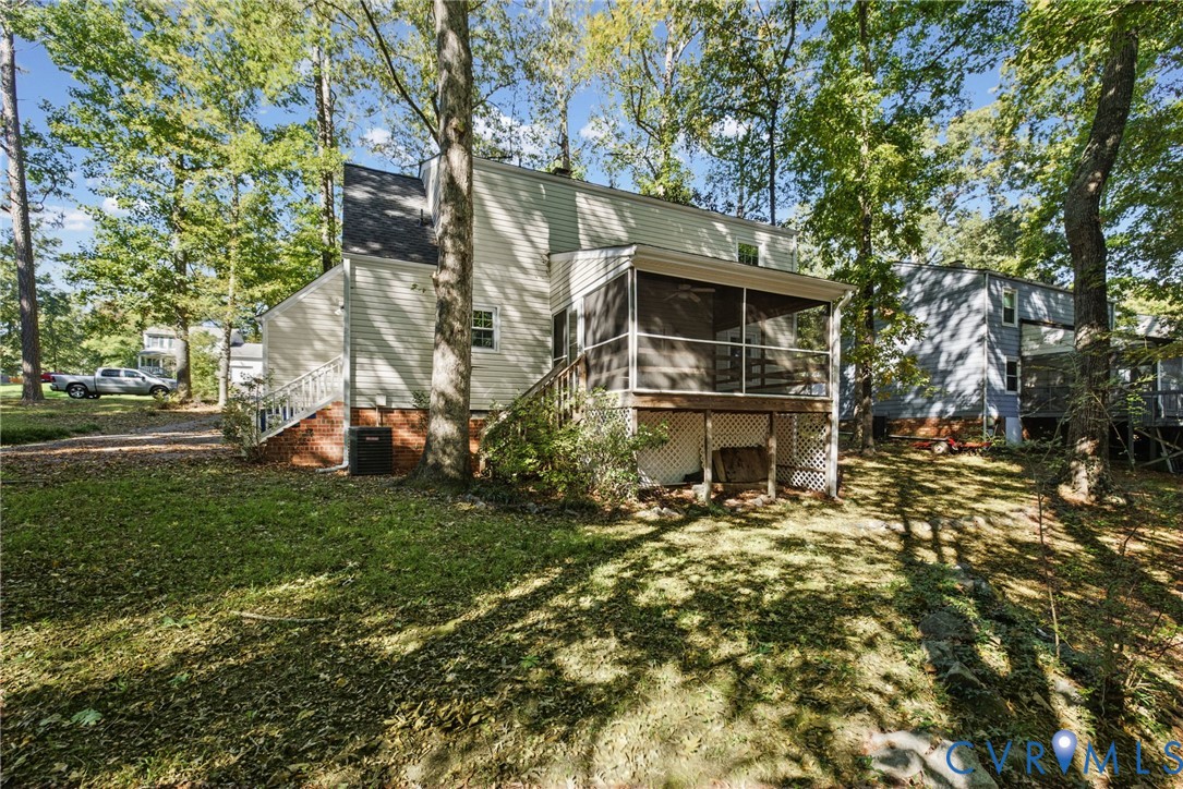 Exterior featuring light-colored horizontal siding, raised screened porch with wooden railing, lattice foundation skirting, and mature trees