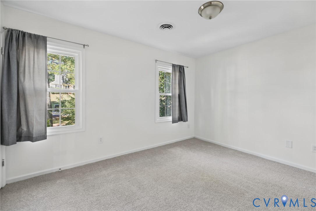 Neutral-toned wall-to-wall carpeting, dual double-hung windows, and a flush-mount ceiling fixture
