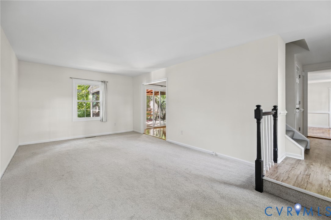 Neutral-toned wall finish, wall-to-wall carpeting, wood-finish flooring at the entryway, and a black-and-white metal balustrade featuring decorative posts Neutral-toned wall finish, wall-to-wall carpeting, wood-finish flooring at the entryway, and a black-and-white metal balustrade featuring decorative posts