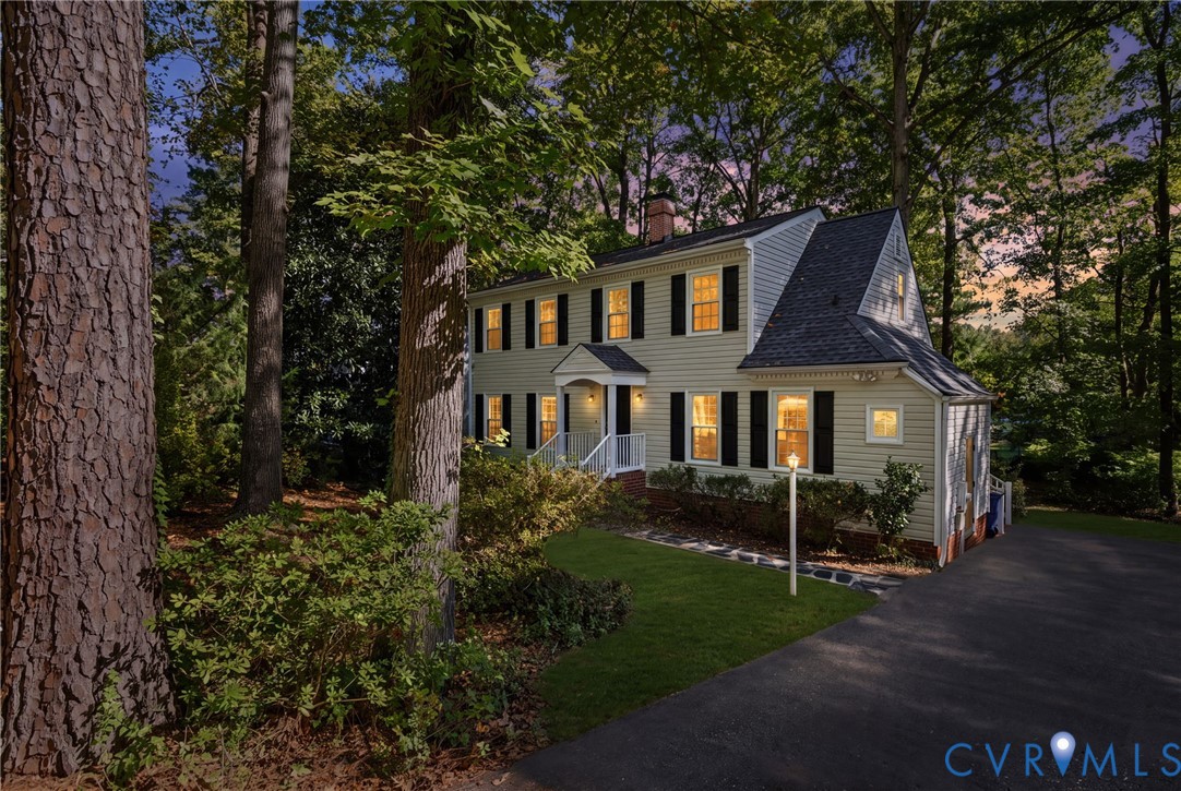 Two-story residence featuring light-colored horizontal siding, black shutters, an asphalt shingle roof, a covered front entryway, and a paved driveway