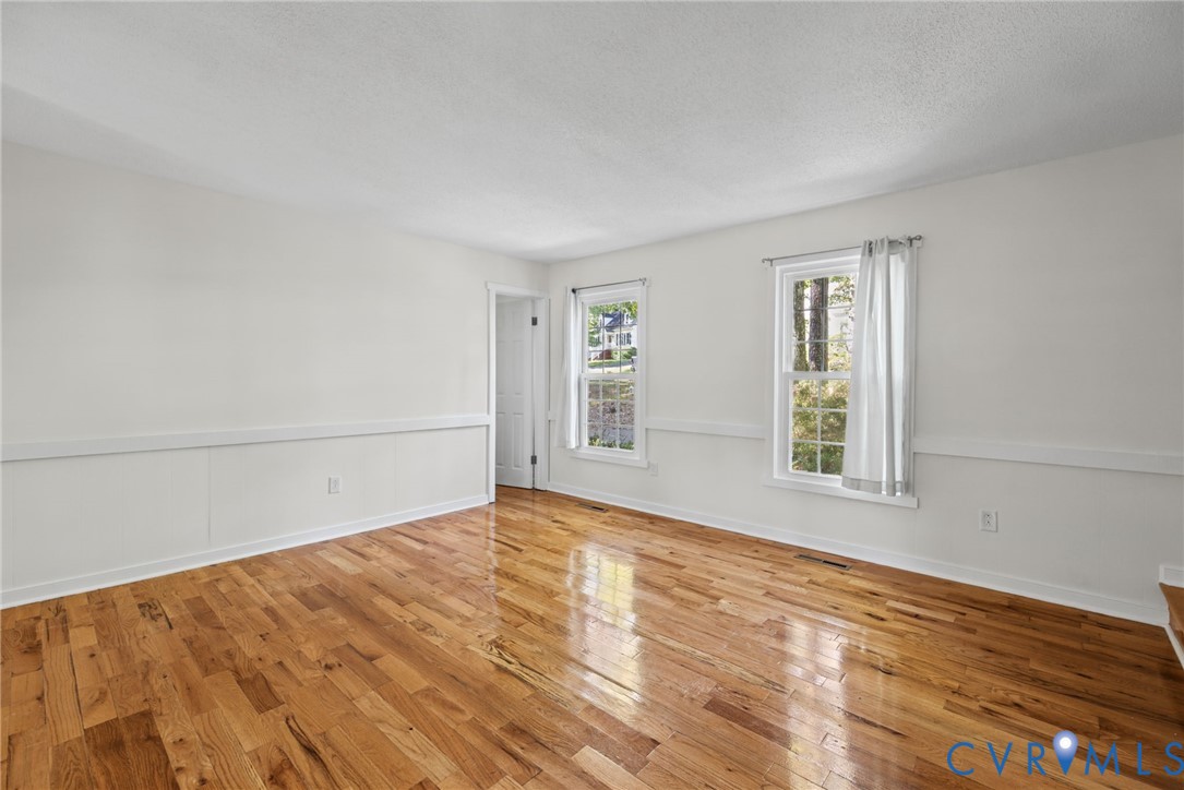 Interior room featuring wood-finish flooring, chair rail molding, and double-hung windows