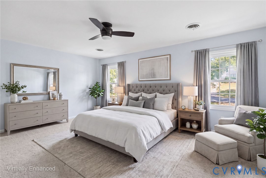Spacious room featuring neutral carpeting, double-hung windows, and a matte black ceiling fan