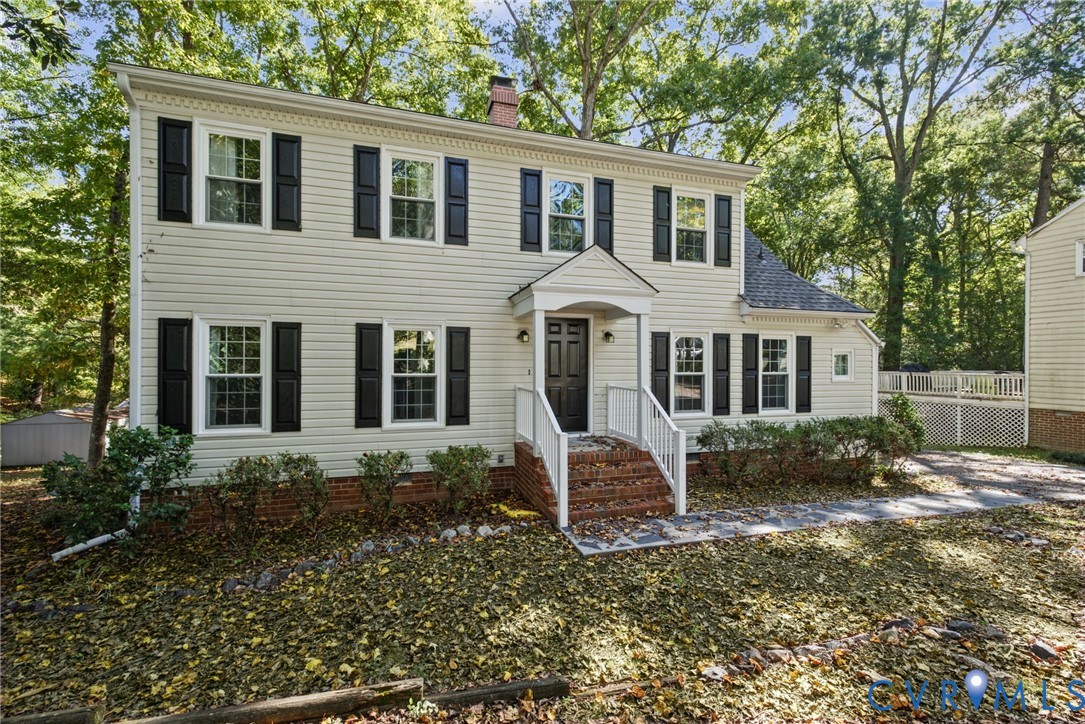 Two-story exterior featuring light-toned horizontal siding, dark window shutters, a brick-front entrance staircase, a covered entryway, and stone-paved walkway Two-story exterior featuring light-toned horizontal siding, dark window shutters, a brick-front entrance staircase, a covered entryway, and stone-paved walkway