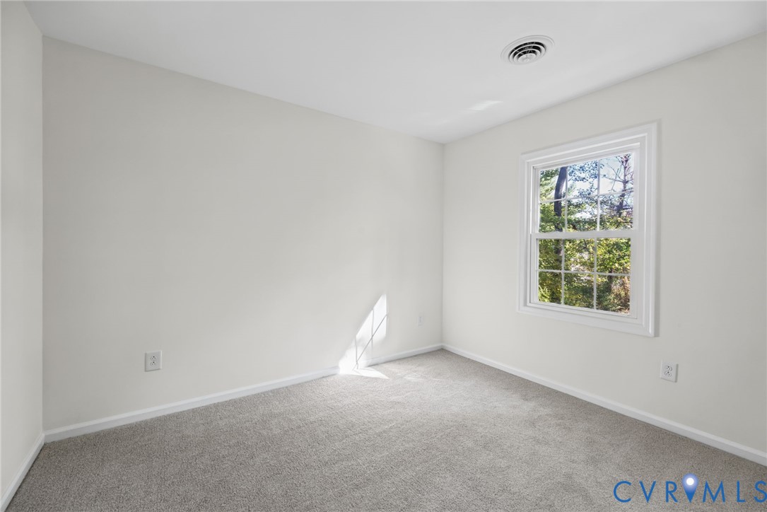 Neutral-toned interior space featuring wall-to-wall carpeting and a multi-pane window with white trim