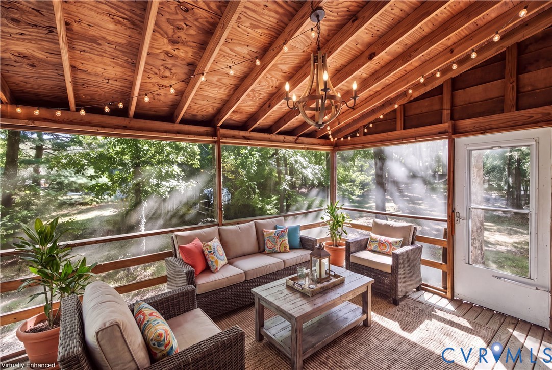 Screened-in porch featuring exposed wood-beam vaulted ceilings, wood plank walls, a decorative multi-light chandelier, and full-perimeter screening