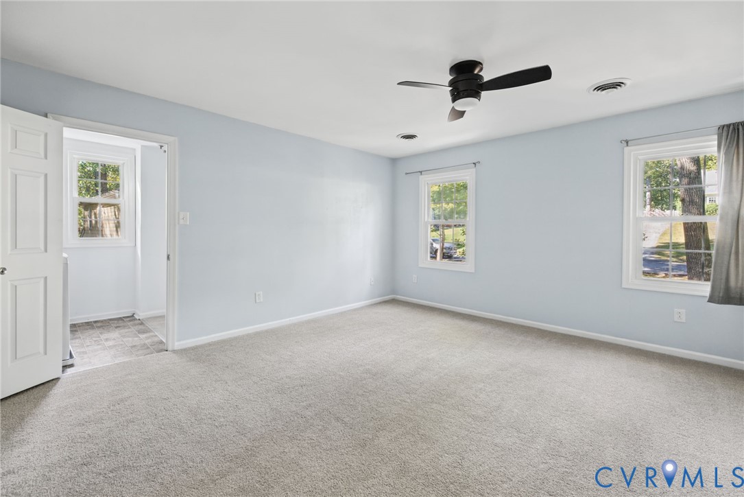 Neutral-toned carpeting, multi-pane windows, and a ceiling-mounted fan with integrated lighting